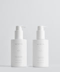 Two white skincare bottles with pump dispensers on a light gray background