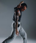 Man in black tank top and gray pants with tattoos on a gray background